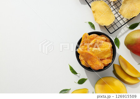 A bowl of dried mango chips with fresh sliced mango 126915509