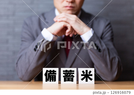 備蓄米のブロックとスーツを着て悩むミドル男性ビジネスマン 126916079
