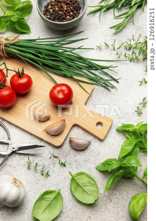 Fresh herbs, spices, tomatoes and garlic creating a frame on kitchen table 126916251