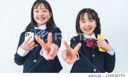 スマホを持ってピースする二人の制服の女の子 126916779