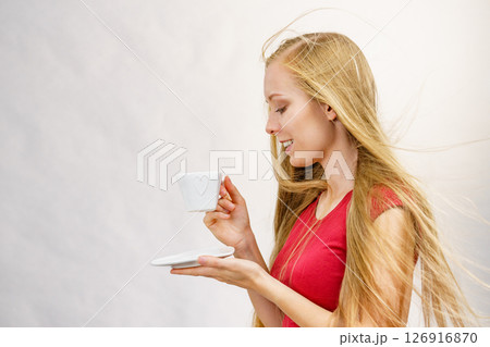 Blonde girl blowing hair holds coffee cup 126916870