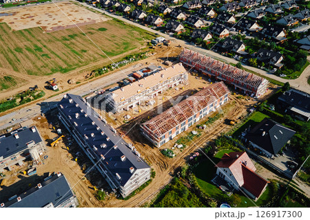Aerial view of large suburban construction site with residential buildings in European suburb. Real estate development in small town, Building new homes Aerial view of large suburban construction site with residential buildings in European suburb. Real estate development in small town, Building new homes 126917300
