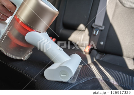 Close up of cleaning car seat upholstery with cordless vacuum cleaner. Process washing vehicle interior. Daily cleaning for comfortable driving car 126917329