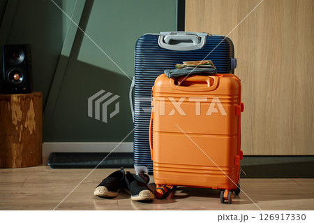 Colorful packed suitcases, documents and shoes stand near door. Departure from home. Tourism, lifestyle or travel concept 126917330