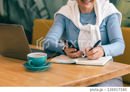 Remote worker mature lady multitasking at cozy cafe 126917380
