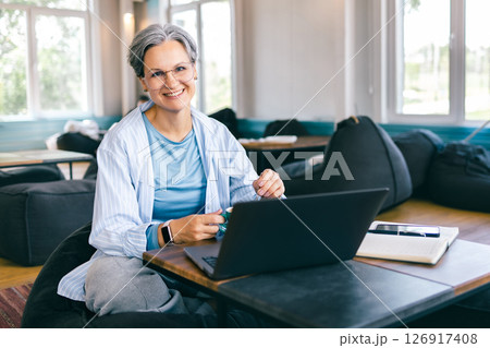 Happy senior woman with gray hair working on laptop and enjoying vibrant life during menopause Happy senior woman with gray hair working on laptop and enjoying vibrant life during menopause 126917408