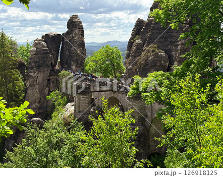 May 2025. The Bastei Bridge in Saxon Switzerland is visible through the greenery of the trees. Saxon Switzerland National Park. Editorial 126918125
