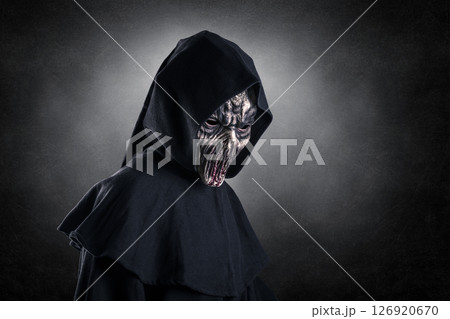 Portrait of a creepy monster with hooded cloak over dark misty background Portrait of a creepy monster with hooded cloak over dark misty background 126920670