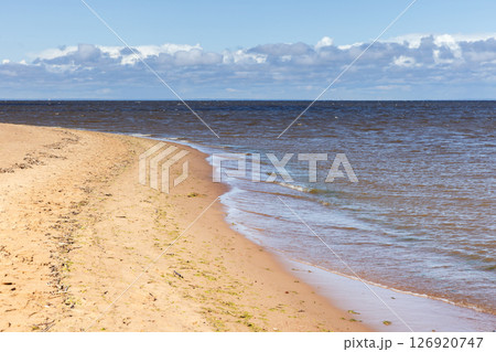 Calm sandy shoreline with soft waves lapping onto the coast 126920747