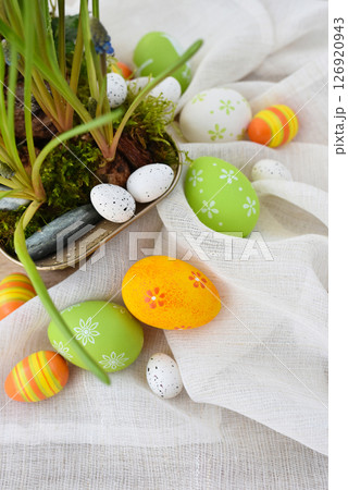 Colorful easter eggs on linen cloth and spring primroses in a pot. Easter still life Colorful easter eggs on linen cloth and spring primroses in a pot. Easter still life 126920943