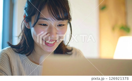 画面を見つめ微笑む20代日本女性 126921378