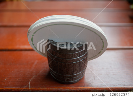 Round white coasters in wooden barrel holder on wooden table surface, concept of bar decor Round white coasters in wooden barrel holder on wooden table surface, concept of bar decor 126922574