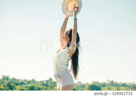 In the photo, the girl stands against the backdrop of a lake and holds her hat high, confidently straightening up 126922731