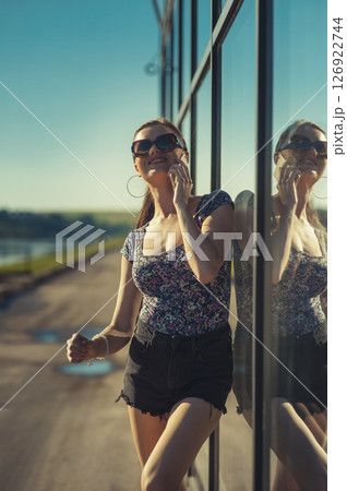 The young lady near the glass surface is engaged in an active phone conversation 126922744