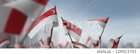 Singapore flags in their hands on a blurred urban background 126923781