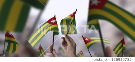 Togo flags in their hands on a blurred urban background 126923783