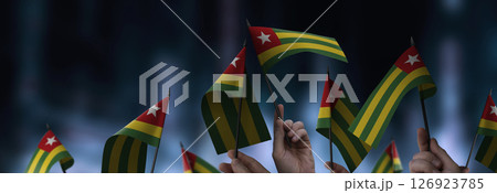 Togo flags in their hands on a blurred urban background 126923785