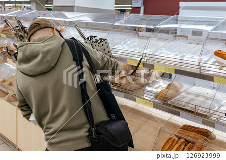 Man choosing bread on the counter. Buying fresh bread. Bakery. Man choosing bread on the counter. Buying fresh bread. Bakery. 126923999