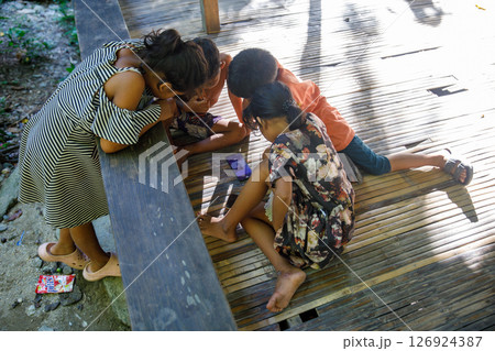 May 25, 2024: Philippines, Filipino children watching smartphone screen together outdoors May 25, 2024: Philippines, Filipino children watching smartphone screen together outdoors 126924387