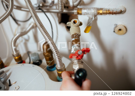 Inspecting a Water Heater with a Flashlight 126924802