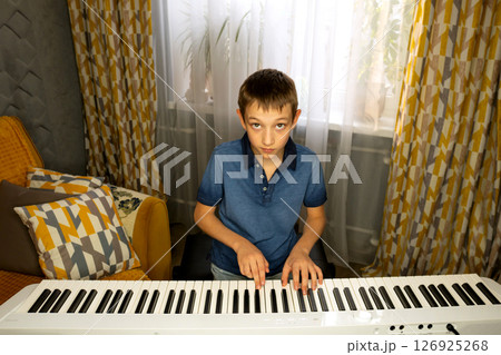 Boy looking up while playing digital piano Boy looking up while playing digital piano 126925268
