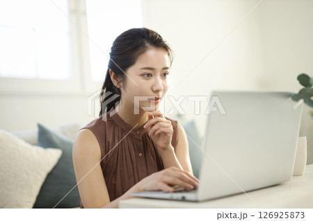リビングでノートパソコンに向かう20代女性 リビングでノートパソコンに向かう20代女性 126925873