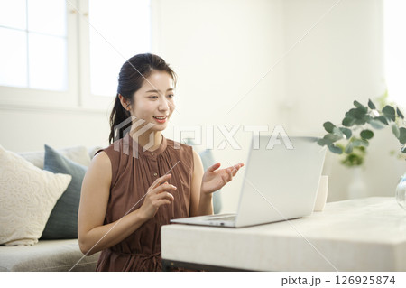 リビングでノートパソコンに向かう20代女性 126925874