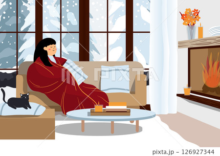 Woman wrapped in a blanket by the fireplace in a cozy room. 126927344