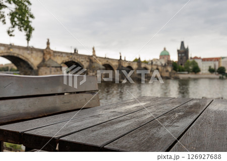 Empty wooden table and bench overlooking charles bridge in prague Empty wooden table and bench overlooking charles bridge in prague 126927688