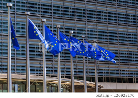 Waving EU flags in front of the Berlaymont building headquarters of the European Commission in Brussels, Belgium Waving EU flags in front of the Berlaymont building headquarters of the European Commission in Brussels, Belgium 126928170