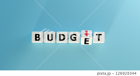 Blocks spell BUDGET with a red downward arrow. Symbolizes budget cuts, financial decrease, expense reduction, or economic challenges. Ideal for finance, accounting, cost management and crisis concepts 126928344