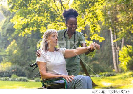 Nurse working with a patient in the park and helping her to do rehabilitation exercising 126928758