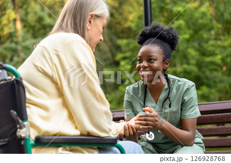 Nurse helping a female patient to exercise hand with a massage ball Nurse helping a female patient to exercise hand with a massage ball 126928768