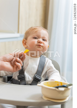 Father and a cute little baby boy having breakfast in the kitchen Father and a cute little baby boy having breakfast in the kitchen 126928859