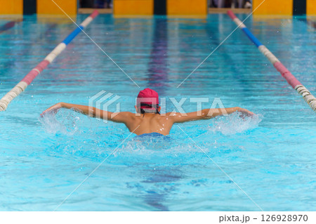 Swimmer child swims butterfly swimming style in a race swimming pool. Water sports and competition, learning to swim classes for children. 126928970