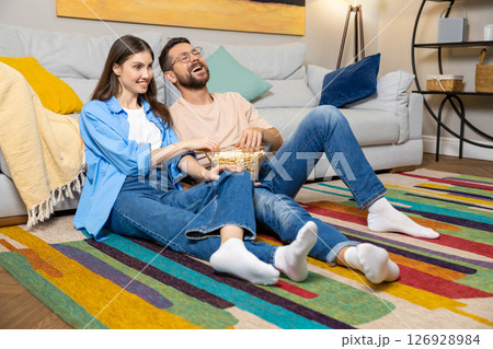 Relaxed couple watching comedy movie online at home sharing food Relaxed couple watching comedy movie online at home sharing food 126928984