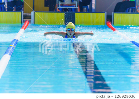 Swimmer child swims butterfly swimming style in a race swimming pool. Water sports and competition, learning to swim classes for children. 126929036