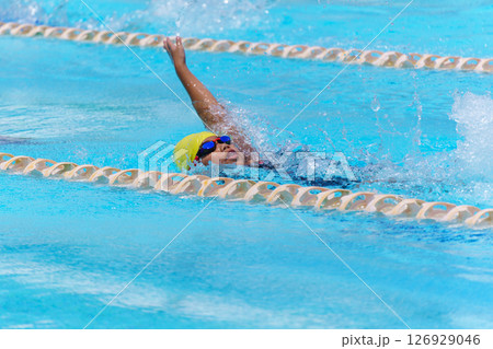 Swimmer child swims backstroke swimming style in a race swimming pool. Water sports and competition, learning to swim classes for children 126929046