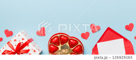 Envelope on colored background for Valentine Day with gift box and chocolate. Heart shaped with gift box of chocolates top view with copy space 126929165
