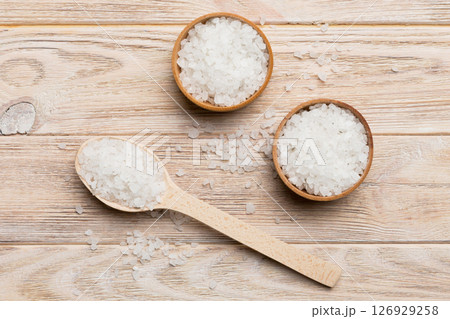 A wooden bowl of salt crystals on a wooden background. Salt in rustic bowls, top view with copy space A wooden bowl of salt crystals on a wooden background. Salt in rustic bowls, top view with copy space 126929258