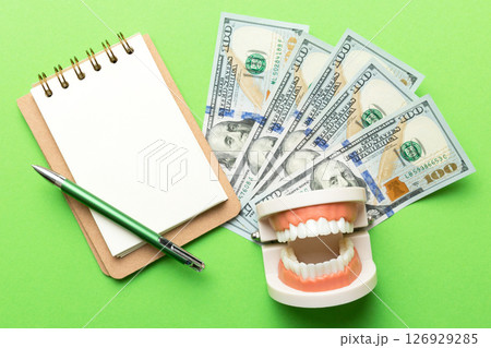 Flat lay composition with educational dental typodont model and money with notebook on colored table, top view. Expensive treatment Flat lay composition with educational dental typodont model and money with notebook on colored table, top view. Expensive treatment 126929285