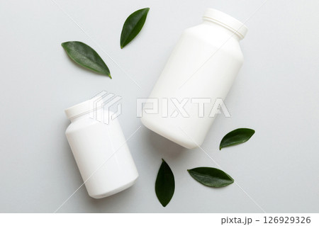 supplement pills with medicine bottle health care and medical top view. Vitamin tablets. Top view mockup bottle for pills and vitamins with green leaves, natural organic bio supplement, copy space 126929326