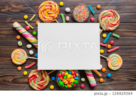 Flat lay holiday composition. Paper blank, lollipop, birthday decorations on Colored background. Top view, copy space for text 126929384