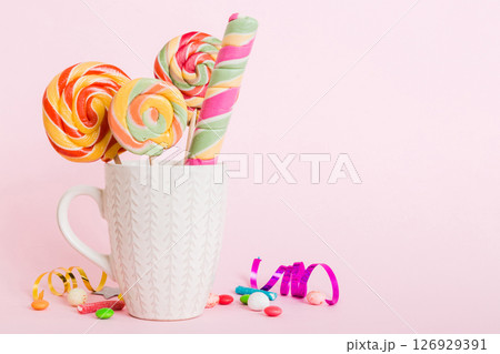 Colorful candies in cup on table on light background background. Large swirled lollipops. Creative concept of a jar full of delicious sweets from the candy store 126929391