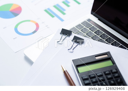 クリップで挟んだ書類とグラフと電卓とパソコン 126929408