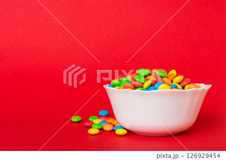 Multicolored candies in a bowl on a colored background. birthday and holiday concept. Top view with copy space Multicolored candies in a bowl on a colored background. birthday and holiday concept. Top view with copy space 126929454