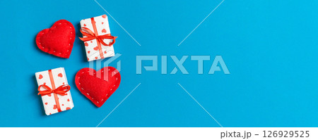 Top view of gift boxes and red textile hearts on colorful background. St Valentine's day concept with copy space Top view of gift boxes and red textile hearts on colorful background. St Valentine's day concept with copy space 126929525