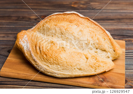 Freshly baked bread on cutting board against white wooden background. perspective view bread with copy space 126929547