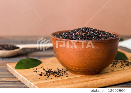 quinoa seeds in bowl and spoon on colored background. Healthy kinwa in small bowl. Healthy superfood quinoa seeds in bowl and spoon on colored background. Healthy kinwa in small bowl. Healthy superfood 126929604