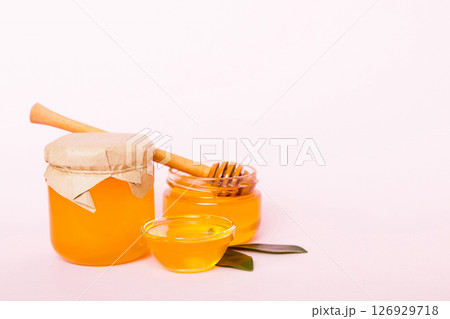 Honey in jar with leaves and honey dipper on colored background top view with copy text Honey in jar with leaves and honey dipper on colored background top view with copy text 126929718